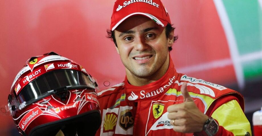 Felipe Massa com roupa da Ferrari, sorrindo, dando joinha com capacete na mão